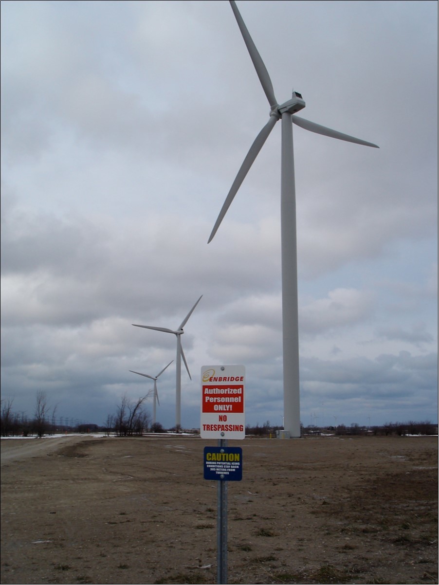 Turbine highway icing caution. Blue Sign Reads “CAUTION – DURING POTENTIAL ICING CONDITIONS STAY BACK 305                 METRES FROM TURBINES”